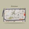 A light-colored fabric storage bag featuring a dinosaur pattern and text, used for a baby changing mat.
