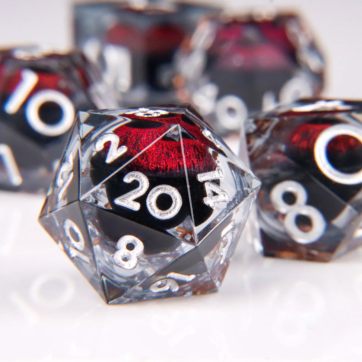 A close-up of a set of liquid core resin dice featuring a dragon eye design, showing various numbers and colors.
