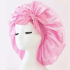 Pink satin silk sleep bonnet tied in a bow displayed on a white mannequin head.