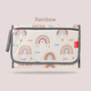 A beige foldable baby changing mat with a waterproof cover and storage bag featuring a rainbow pattern.