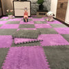 A purple and gray interlocking foam floor mat pattern with a small doll and a white plush toy on the surface.