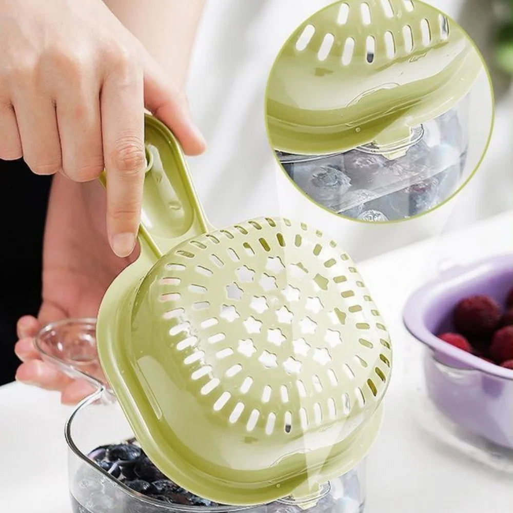 A hand is holding a green double-layer fruit washing and draining basket with a perforated top, showing its use for washing f