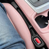 A close-up view of a pink car seat gap filler and organizer with a black handle and red button.