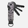 A minimalist aluminum key organizer with a black handle and a metal key attached.