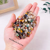 A hand holds a pile of mixed natural crystal gravel stones and gemstone chips for home decor