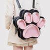 A black backpack with pink lining and multiple pockets shaped like cat paw prints, worn by a person.