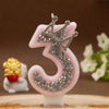 Pink rhinestone crown number candle shaped like the number 3 on a white base