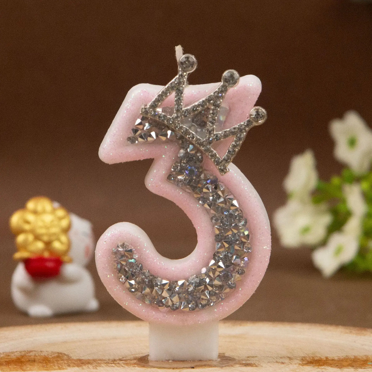 Pink rhinestone crown number candle shaped like the number 3 on a white base