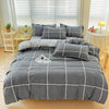 A gray and white plaid bedding set featuring a duvet cover, fitted sheet, and pillows on a bed.