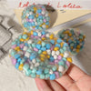 A hand holds a translucent squishy stress ball filled with colorful, soft beads.
