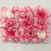 A dense wall panel of pink and white silk rose flowers for weddings and events.