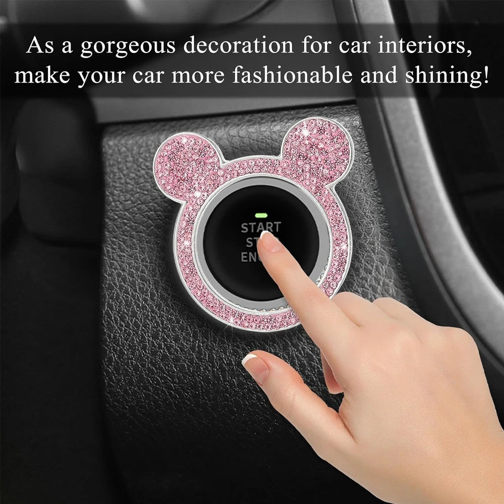 A hand presses a pink glittery bear-shaped ignition button on a car interior panel.