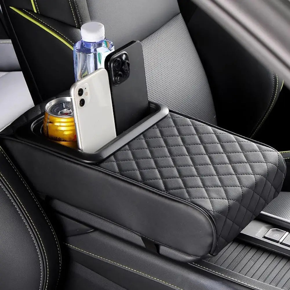 A black car center console armrest cushion with a diamond pattern and integrated cup holders holds a smartphone and a water b