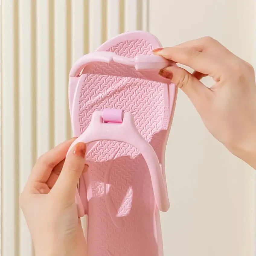 A hand is holding a pink foldable EVA travel slipper, showing the texture and design of the product.