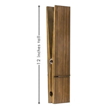 A rustic wooden wall-mounted towel clip with a vertical design and a metal hook.