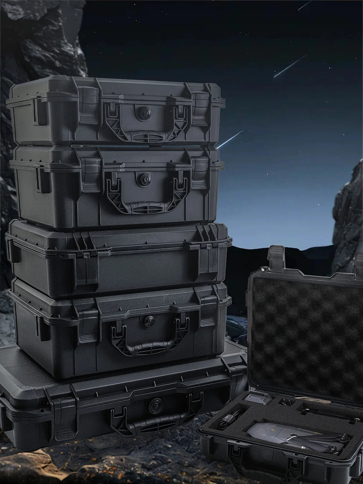 A stack of dark gray hard shell protective storage cases for tools and instruments resting on a rocky surface.
