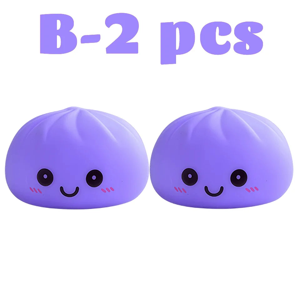 Dos juguetes blandos de dumplings morados brillantes con expresiones faciales lindas