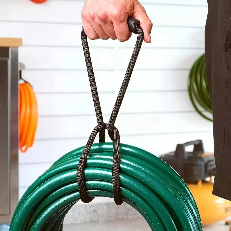 A hand is holding a heavy-duty hook and loop storage strap with a black handle, positioned over a green coiled cable.
