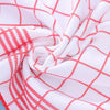 White fabric with a red checkered pattern, folded and draped.