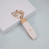 A beige TPU key fob cover with a gold-tone chain and ring attached, resting on a light gray surface.