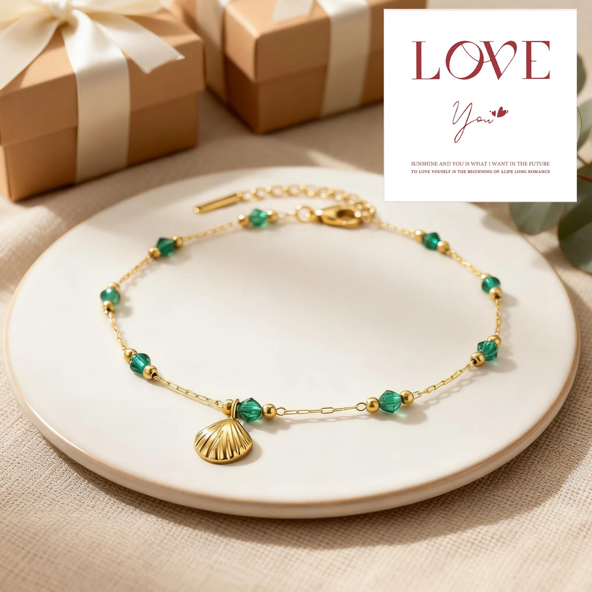 A delicate gold chain anklet featuring small green shell beads displayed on a white plate.