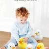 A toddler is playing with a yellow wind-up walking chicken toy and several white chicks.