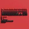 A close-up view of a red PBT double-shot keycap set with gradient colors arranged on a red background.