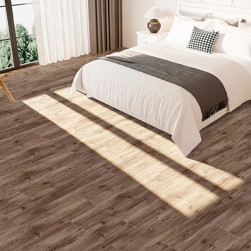 A close-up view of light brown wood grain floor tiles casting long shadows across a bedroom floor.