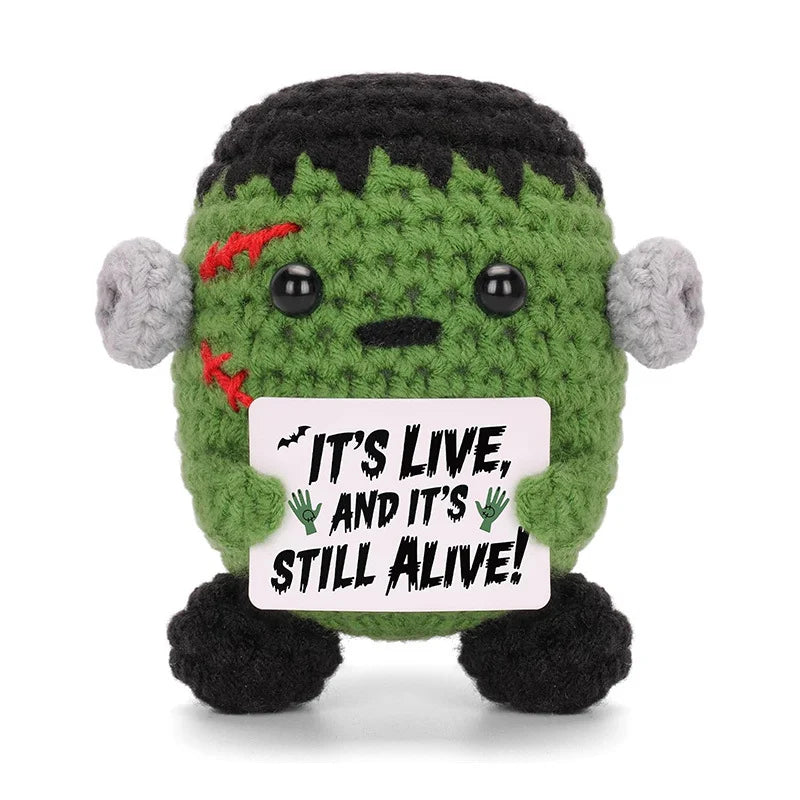 A handmade crochet animal doll with green body and gray ears, featuring a card that reads It's live and it's still alive.