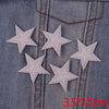 Five silver glitter star iron-on embroidered patches sewn onto a denim fabric.