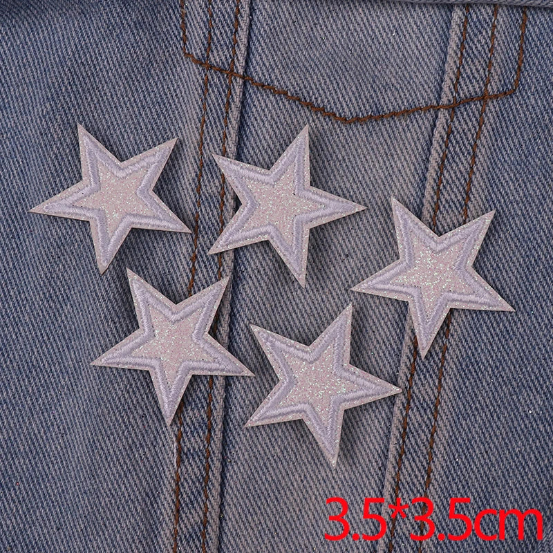 Five silver glitter star iron-on embroidered patches sewn onto a denim fabric.