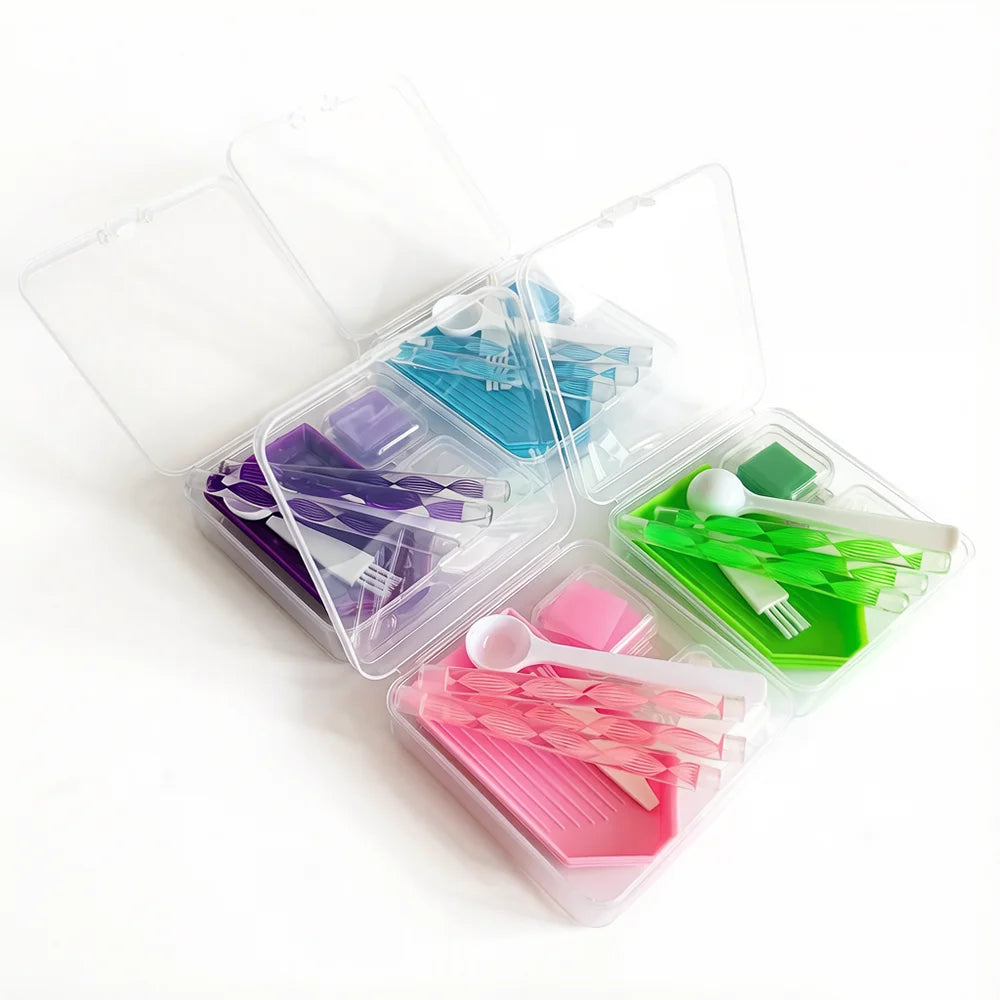 A clear storage box containing various diamond painting tools and accessories like needles, tweezers, and paint palettes.