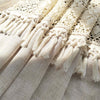 Beige sheer curtain fabric with delicate lace trim and tasseled fringe