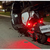 A black motorcycle with a white light is parked on an asphalt road with a red painted line.