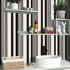 A bathroom shelf display featuring a white vessel sink, wooden storage basket, and various toiletries against black and white