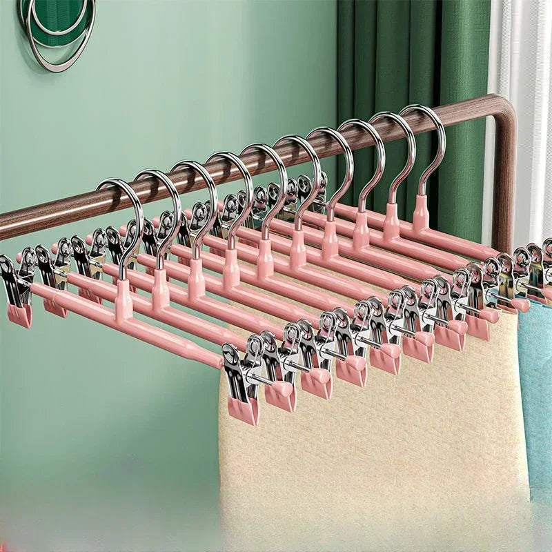 A set of five pink anti-slip stainless steel hangers with clips displayed on a wooden rod.