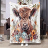 A flannel blanket featuring a painting of a brown Highland cow surrounded by colorful floral elements.