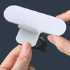 A hand is lifting a white silicone toilet lid lifter with a self-adhesive hook.