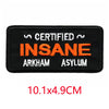 Black embroidered iron-on letter patch with the text Certified Insane Arkham Asylum in orange and white thread.