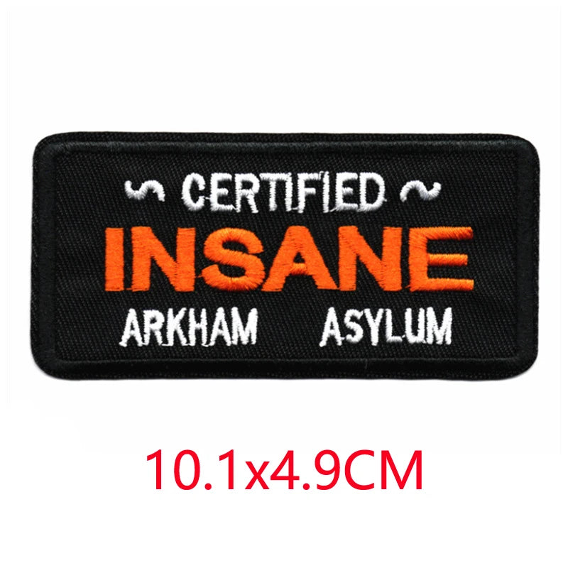 Black embroidered iron-on letter patch with the text Certified Insane Arkham Asylum in orange and white thread.