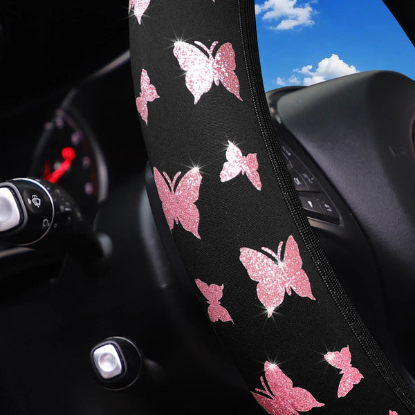 A close-up of a black glitter butterfly patterned steering wheel cover with a pink glitter design.