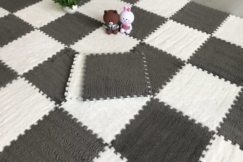 Two small plush bears sitting on a gray and white checkered soft interlocking floor tile pattern.
