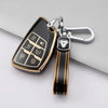 A black and gold TPU car key fob cover attached to a silver keychain with a black leather strap.