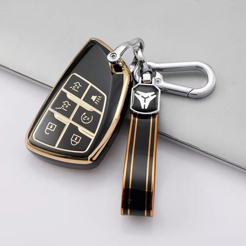 A black and gold TPU car key fob cover attached to a silver keychain with a black leather strap.