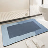 A rectangular blue bath mat with a gray accent placed on a white bathroom counter next to a toilet.