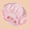 A pink satin wide brim shower cap is shown in a soft, draped style.