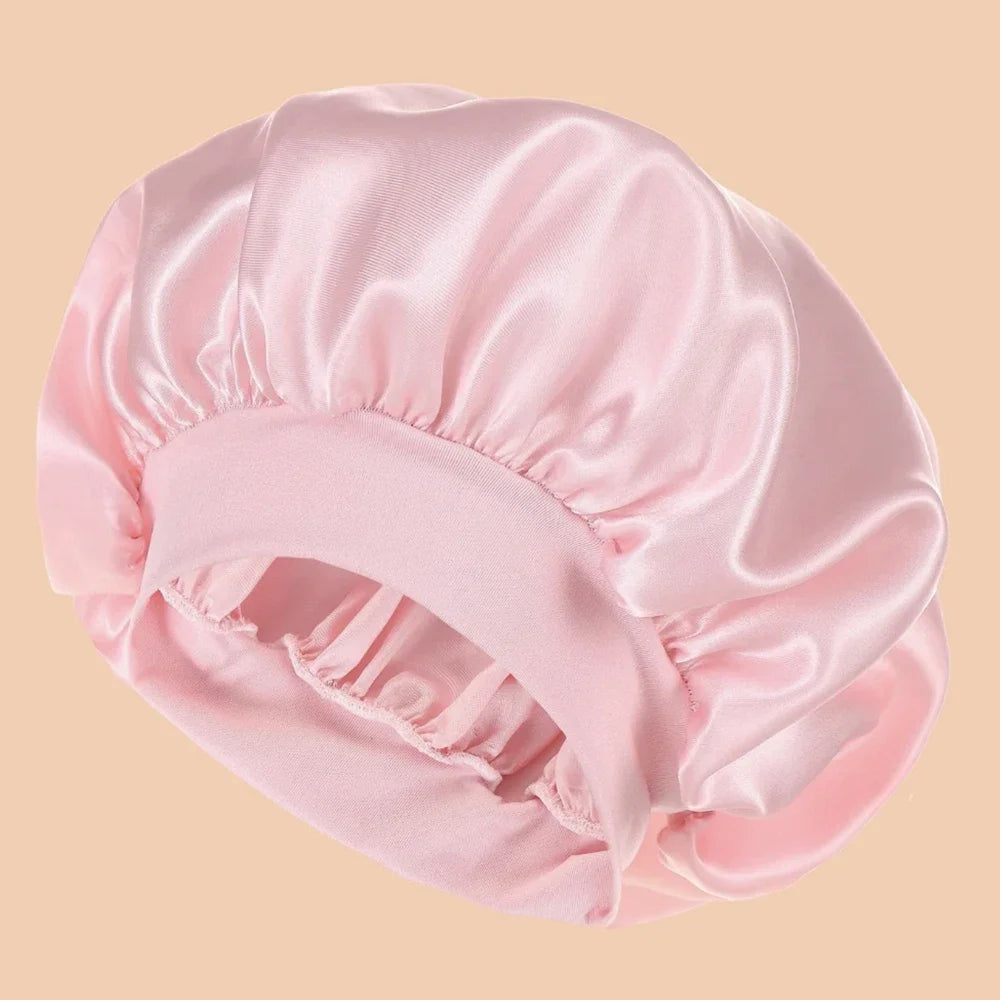 A pink satin wide brim shower cap is shown in a soft, draped style.