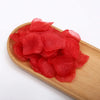 A pile of bright red silk rose petals on a wooden serving board.