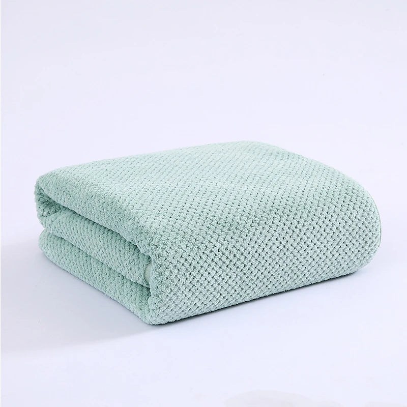 A folded mint green knitted bath towel with a textured surface.