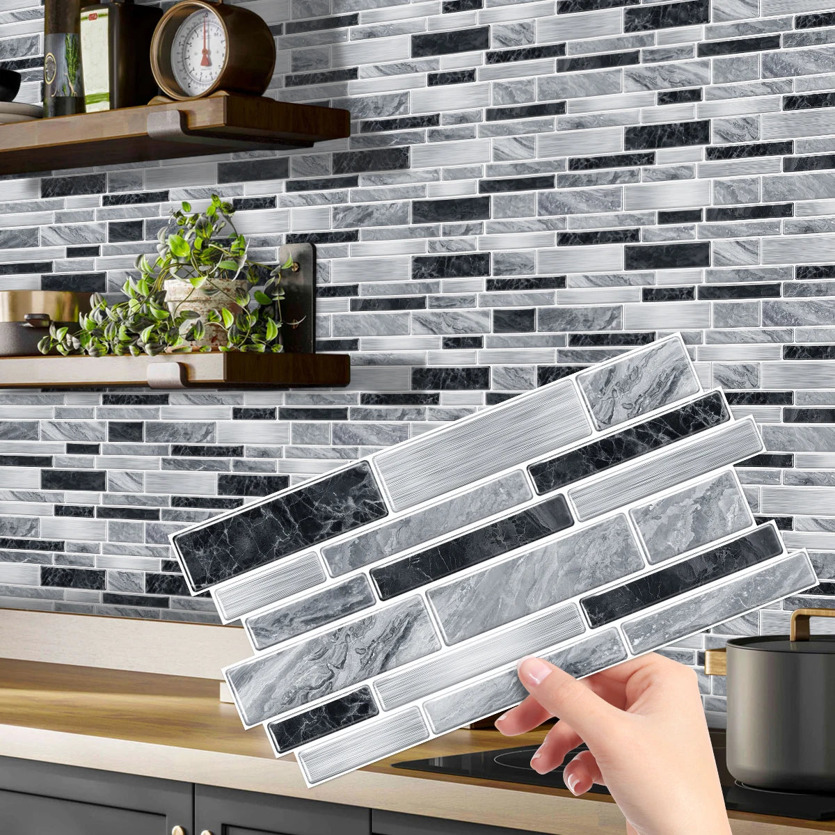 A hand is placing peel-and-stick tile stickers onto a gray and black marble backsplash.